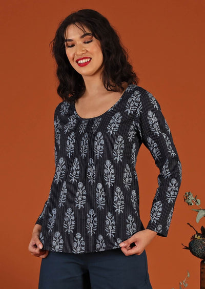 Model in long sleeve cotton blouse with floral motif and scoop neck