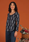 Model with dark hair in blouse with floral motif and scoop neck