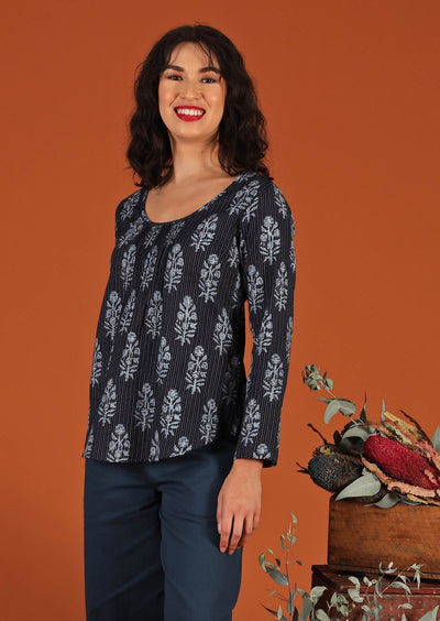 Model with dark hair in blouse with floral motif and scoop neck