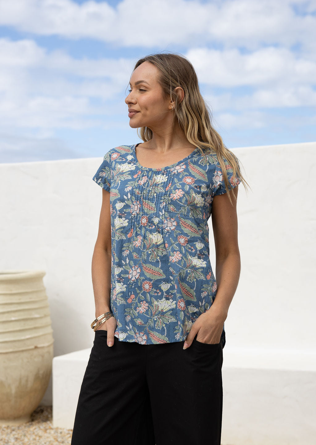 Woman wearing a blue cotton top with pink, lemon yellow and green floral print