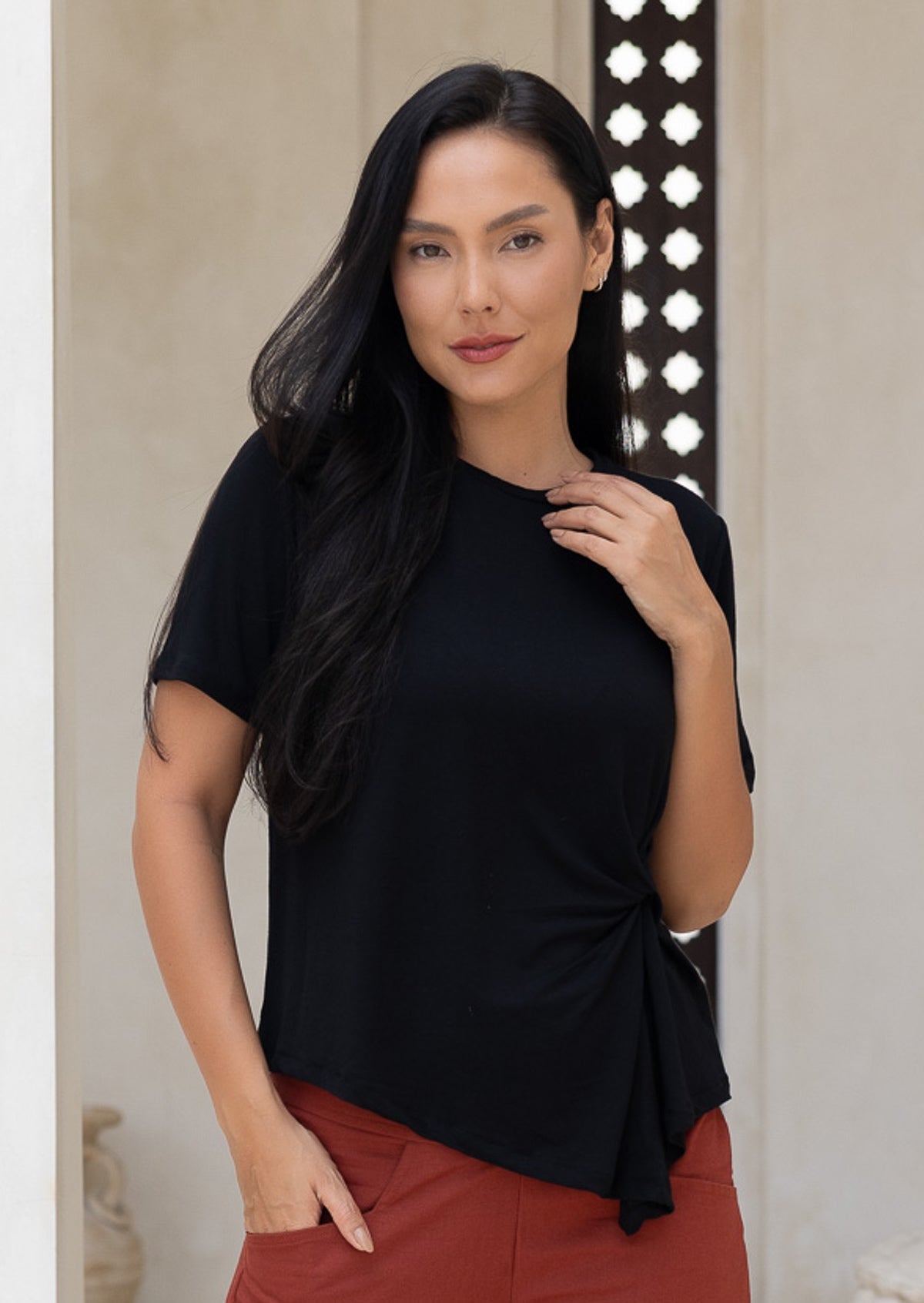 Woman wearing a black stretch rayon top with an asymmetrical front hem