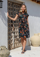Woman wearing a black cotton floral dress with protea print 
