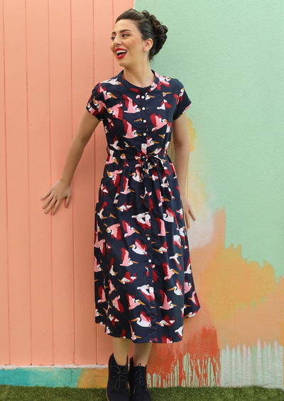 Model with dark hair wearing navy blue retro style dress with pelican print