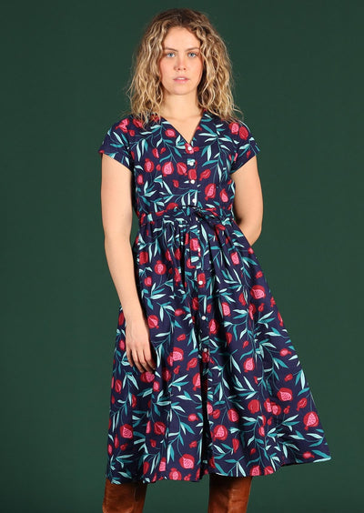 Model wears blue 100% cotton dress with pink and red pomegranate print