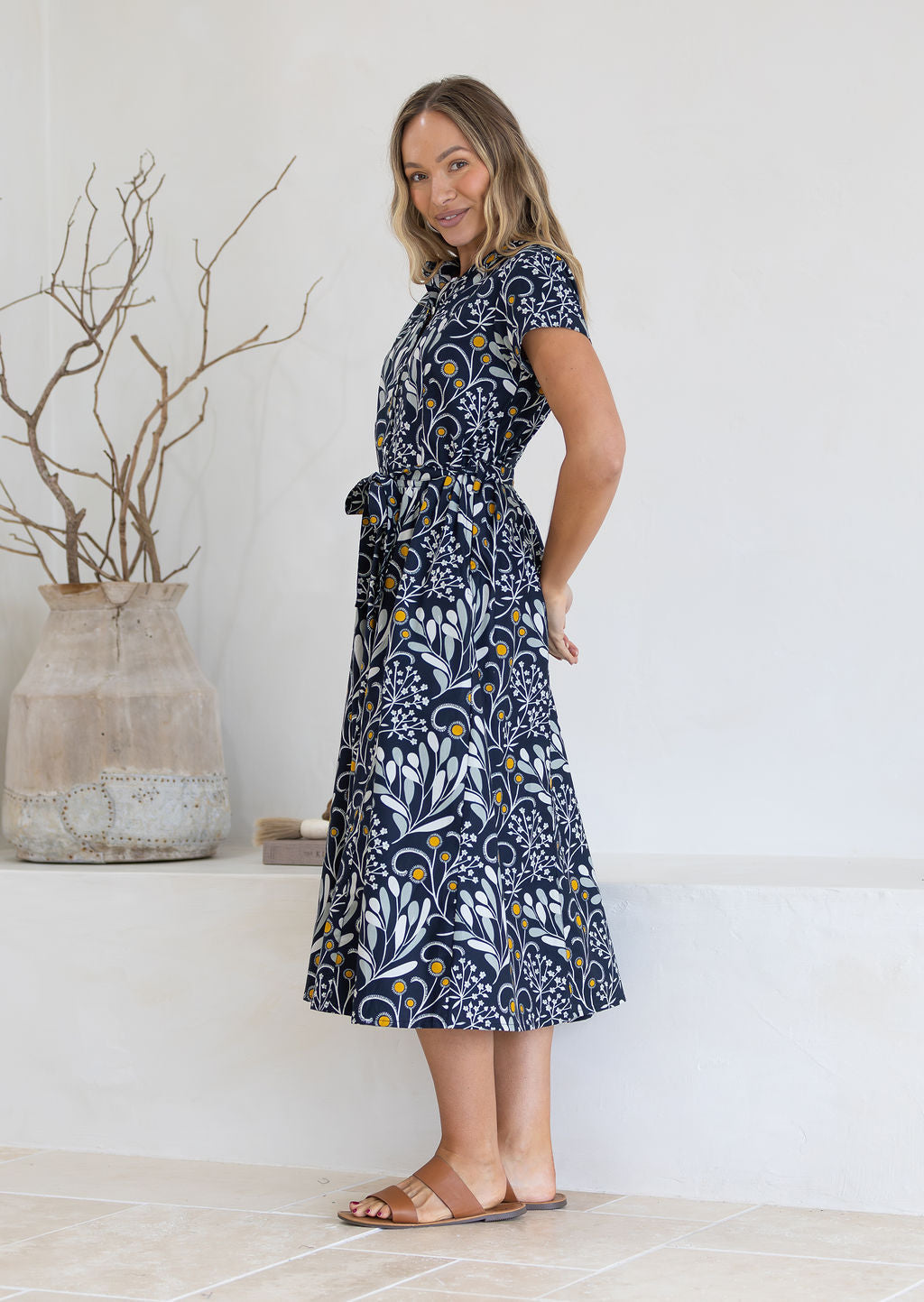 Woman wearing black cotton midi dress with hands behind her back 