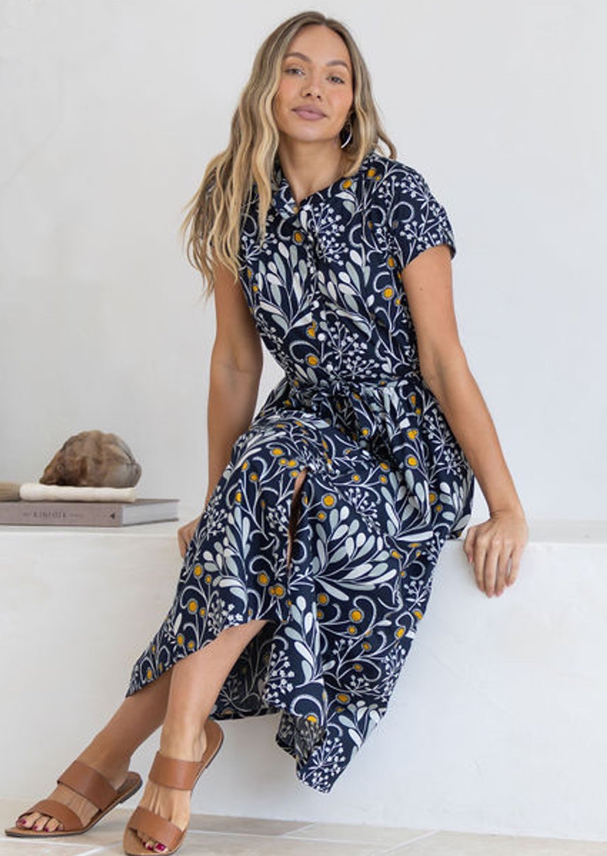 Woman wearing a black cotton midi dress sitting on a white surface.