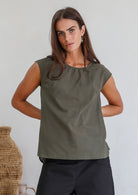 Woman wearing a muted green sleeveless cotton sleeveless top with a round neckline