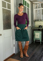 woman wearing a cotton corduroy skirt in luxurious, deep blue-green with both hands in pockets