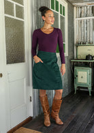 woman wearing a cotton corduroy skirt and basic top standing indoors with one hand in pocket