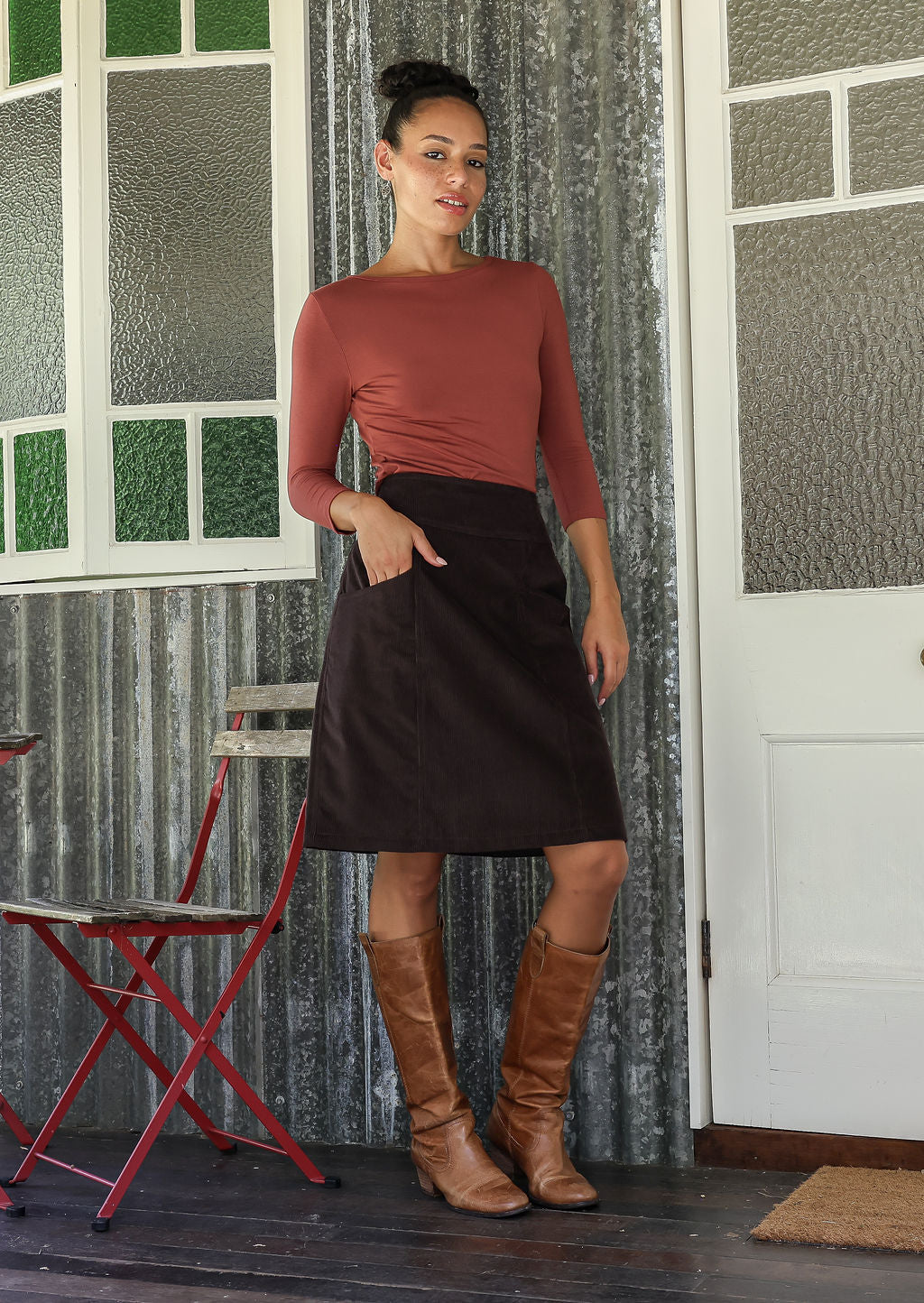 woman wearing a cotton corduroy skirt in dark, neutral chocolate brown with one hand in pocket