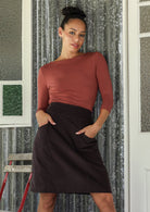 Woman wearing a basic top and cotton corduroy above knee length skirt in dark, neutral chocolate brown