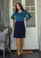 woman wearing a cotton corduroy skirt in  deep, rich, and slightly muted navy blue paired with a basic top