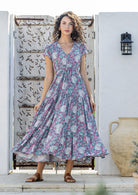 Woman stands in rayon maxi dress with tulip sleeves, V-neckline and buttoned bodice