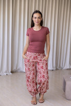 Woman wearing a basic top and gentle cream based cotton floral pants, with her hand in pocket