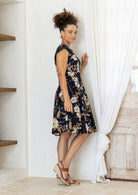 Model posing sideways in a beautiful 100% cotton dress with black based floral print