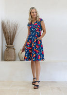 Model is wearing a 100% cotton dress in royal blue based floral print with cap sleeves and pockets