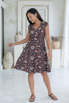 Model poses in fit and flare, knee length cotton dress with crossover bodice, v-neckline and full a-line skirt.