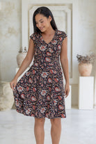 Model holds one side of the 100% cotton retro style Indian floral print dress with cap sleeves, pockets and crossover bodice.