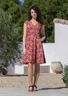 Woman wearing warm toned cotton knee length dress in pink, maroon, brown, peach and khaki palette