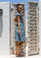 Model posing sideways in a beautiful cotton dress with teal based floral print.