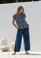 Woman wearing a navy blue based relaxed fit, shirt style floral cotton top with plain pants.