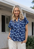 Woman poses in relaxed fit cotton short sleeve top with rolled cuffs sleeves, collar and V neckline.