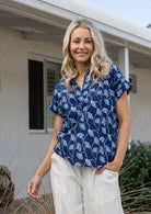 Woman wearing a navy blue based relaxed fit, shirt style floral cotton top with plain pants.