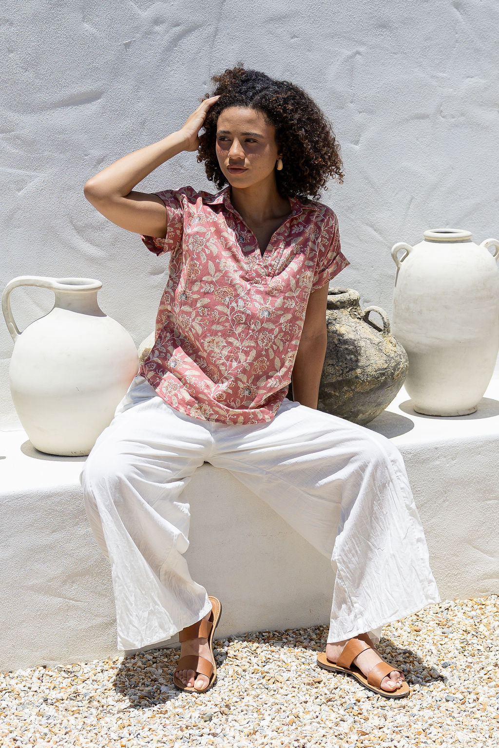 Woman sitting outdoors wearing 100% cotton top with white pants 