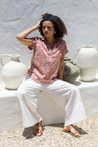 Woman sitting outdoors wearing 100% cotton top with white pants 