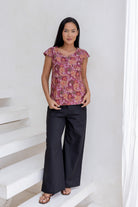 Woman wearing a floral cap sleeve top  blending pink, maroon, brown, peach and khaki palette.