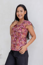 A woman wears a 100% cotton tailored top with short cap sleeves and a round neckline with a keyhole cutout, paired with black cotton pants