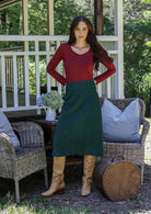 Woman in a red top and green cotton corduroy A-line midi length skirt standing with hands on hips