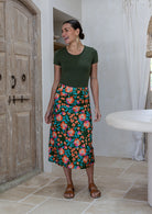 Woman wearing a basic top and olive green based skirt in a indoor setting