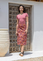 Woman wearing floral print mid length skirt with side zipper and belt loops.