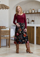 Woman wearing a black based multi-coloured floral print cotton velvet midi length A line skirt with belt loops.
