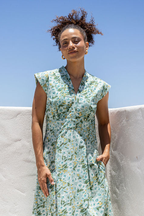 Woman wearing a retro style cotton dress with side zipper, cap sleeves and A line skirt in sage green based floral print