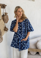Woman wears 100% cotton relaxed fit top in navy based floral print with an asymmetrical hem line.