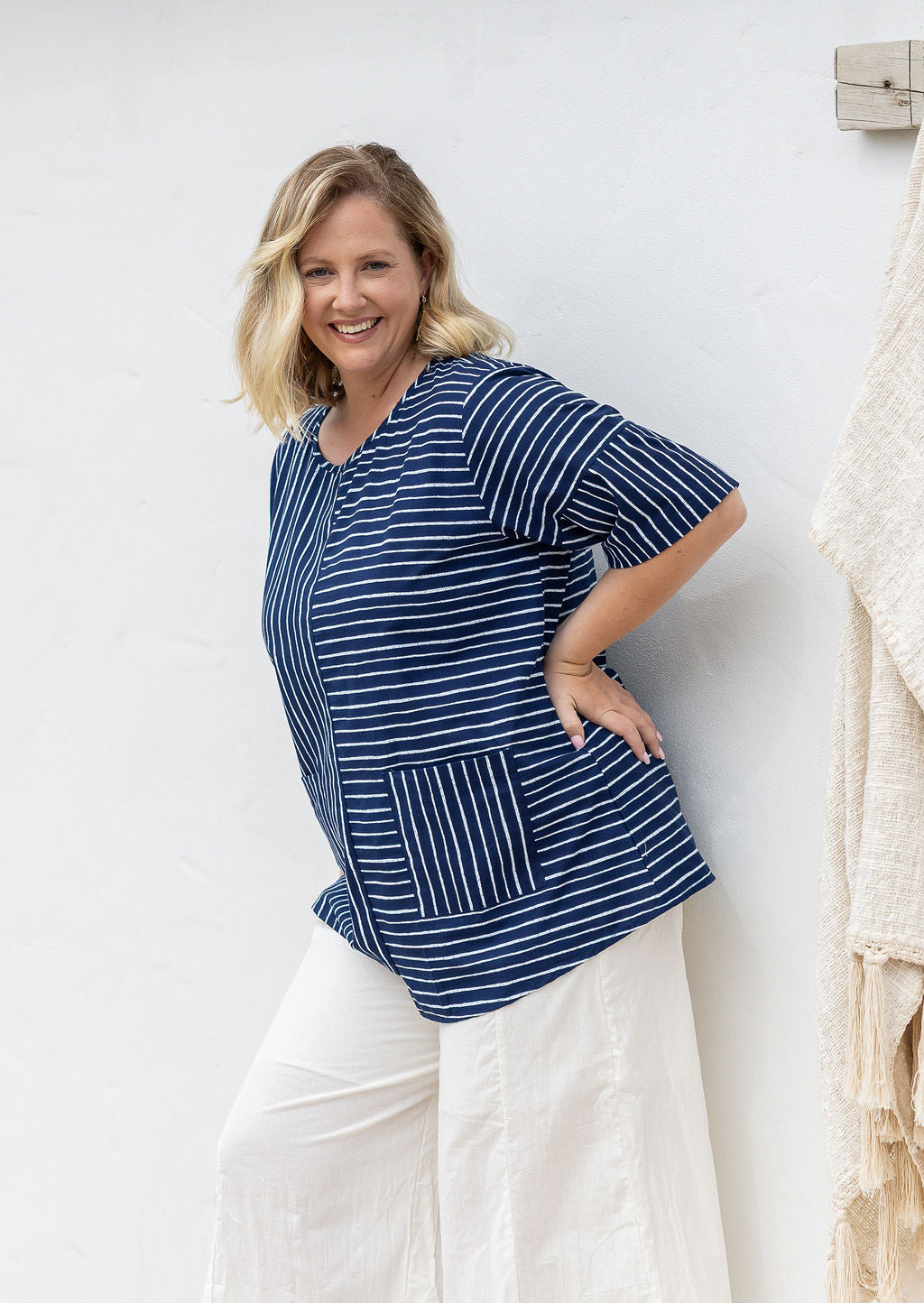 Woman wears a navy and white striped 100% cotton relaxed fit top with short sleeves and front pockets