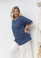 Woman wears a navy and white striped 100% cotton relaxed fit top with short sleeves and front pockets
