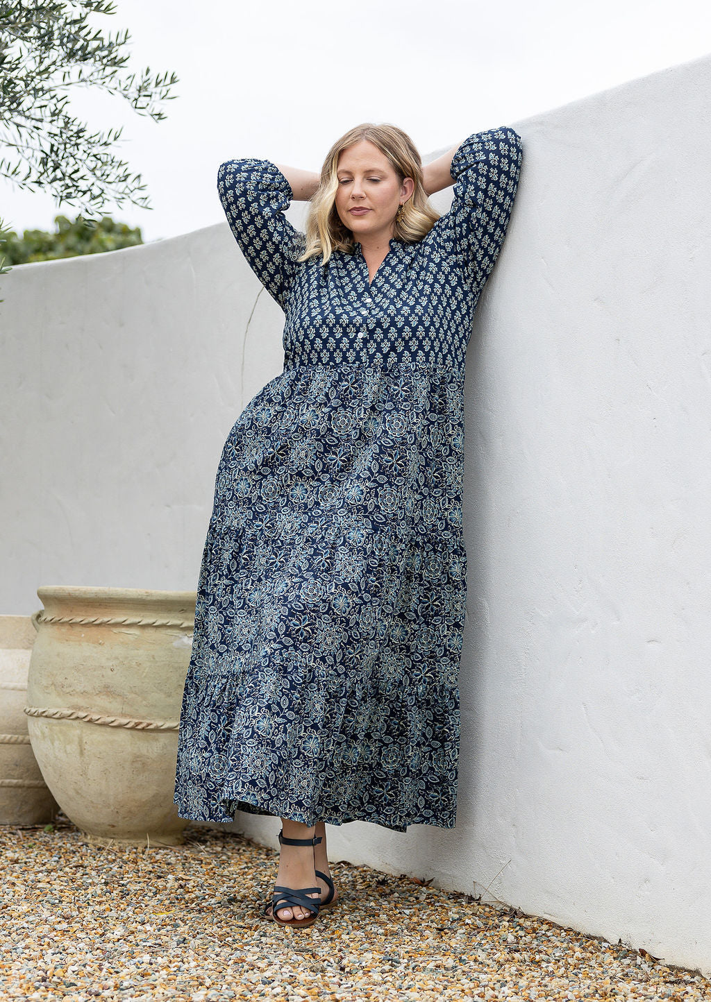 Woman standing in navy blue based 100% cotton flowy tiered maxi dress with 3/4 sleeves, buttoned bodice and pockets 