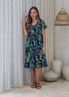 Woman in a cotton navy based floral button through dress with short sleeves and a V-neckline