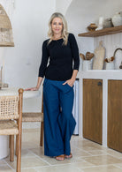 Woman wearing a rayon boat neck black 3/4 sleeve top paired with plain pants