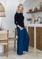 Woman standing sideways wearing a 100% rayon black top paired with plain pants