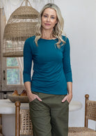 Woman wearing a rayon jersey boat neck sleeve top in teal, with 3/4 sleeves