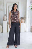 Model stands in black cotton pants and relaxed fit floral print top with round neckline, sleeveless design and side bust darts.