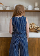 Model stands backwards in sleeveless cotton top in navy based print with high round neckline and side bust darts.