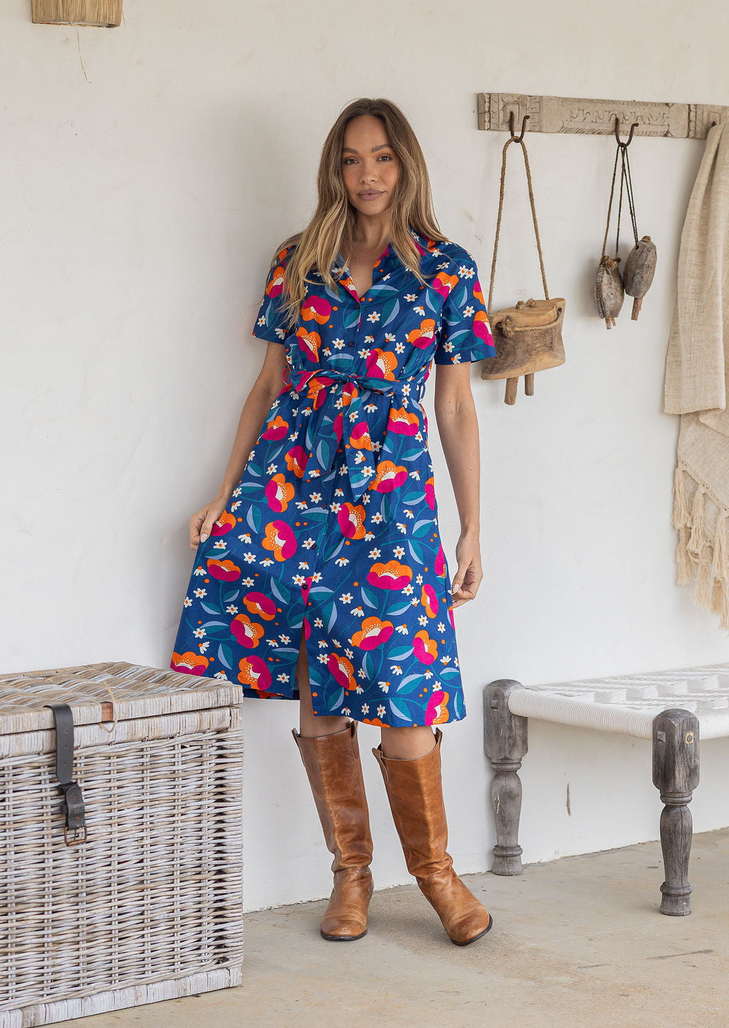 A woman wearing a short-sleeve midi dress with florals on a royal blue background