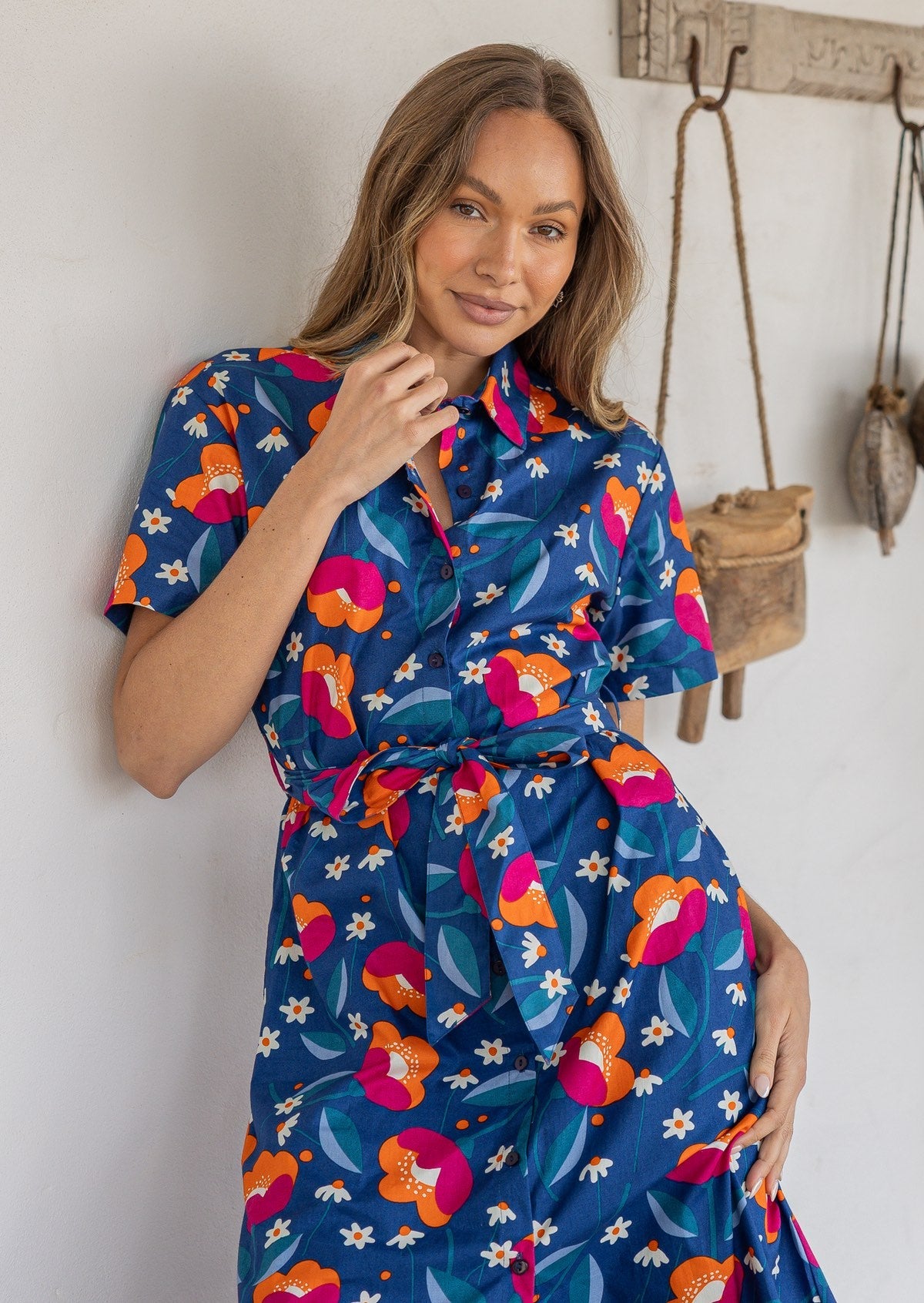 Woman wearing a 100% cotton dress in blue based floral print with collar neckline and pockets