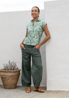 Woman wearing a slim fit button up shirt with shell buttons, structured collar and folded cuff sleeves