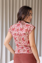 woman standing backwards wearing a gentle cream based floral printed slim fit shirt against a white background. 